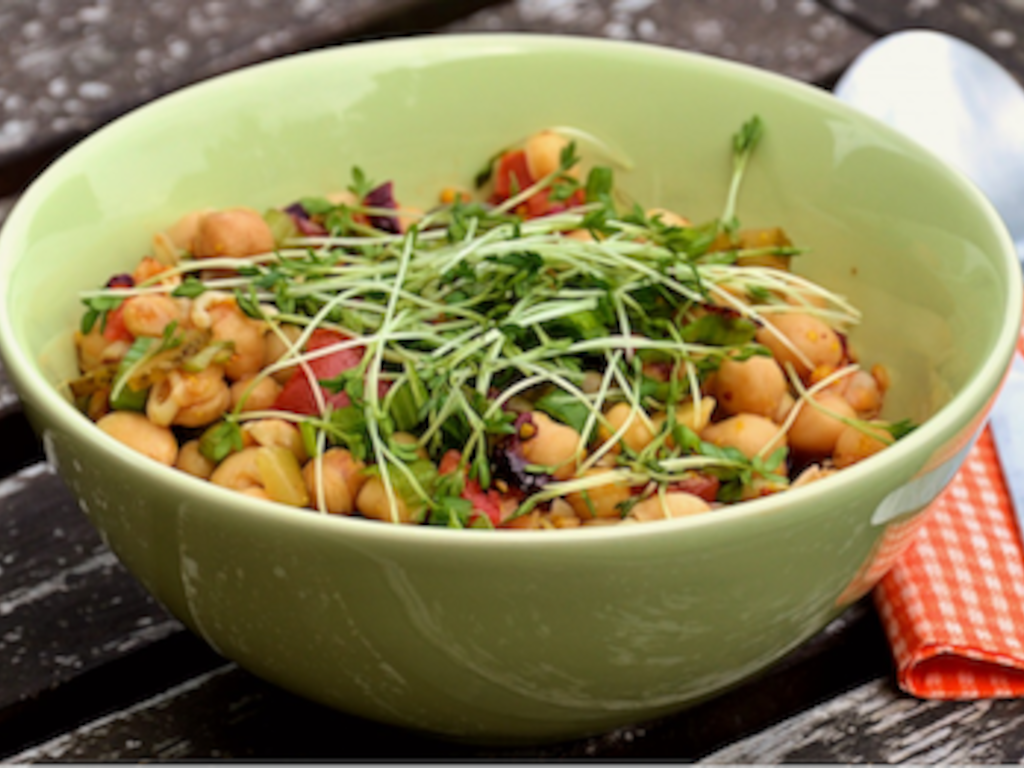 A bowl of fresh vegetables with hands clasped in gratitude.