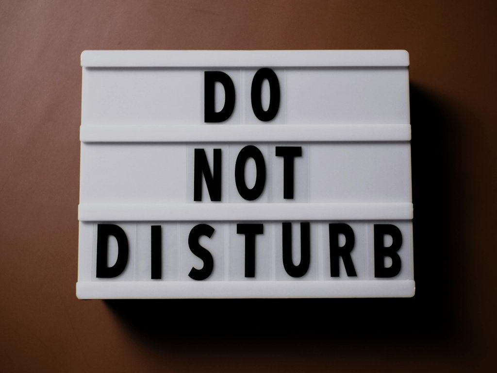 A desk with a notebook and phone set to Do Not Disturb.